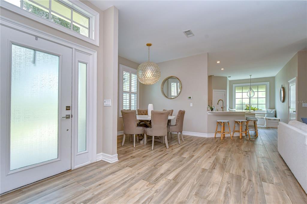 An open-concept dining area and kitchen featuring wood-look flooring and a modern globe pendant light — 3530 FOX SQUIRREL LANE, VALRICO, FL