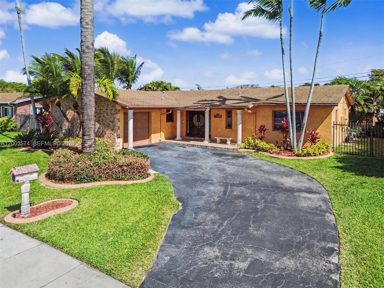 A single-story house with a curved driveway, stone accents, and palm trees in the front yard — 9837 SW 194th St, Cutler Bay FL 33157, CUTLER BAY, FL
