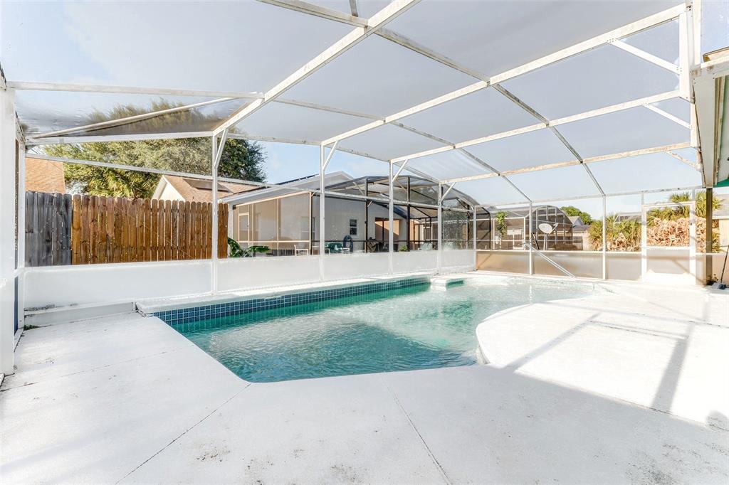 A white single-story house with a two-car garage and a palm tree in the yard — 7813 TURKEY OAK LANE, KISSIMMEE, FL