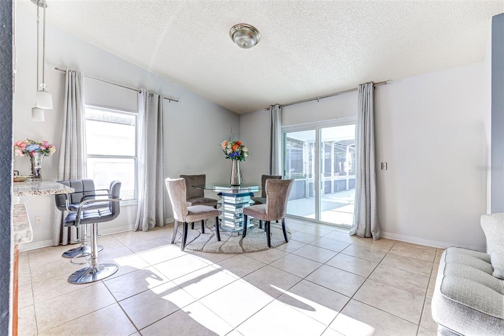 A swimming pool enclosed by a white screen cage sits beside a bright turquoise wall — 7813 TURKEY OAK LANE, KISSIMMEE, FL