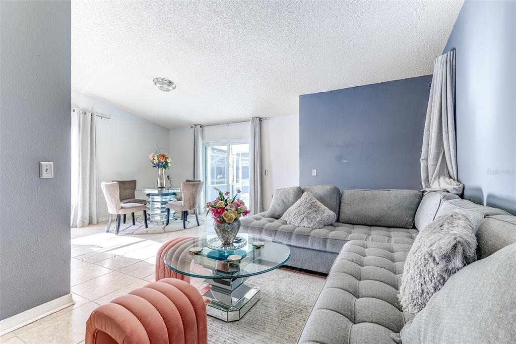 A dining area features a glass table, four upholstered chairs, tile flooring, and sliding glass doors — 7813 TURKEY OAK LANE, KISSIMMEE, FL