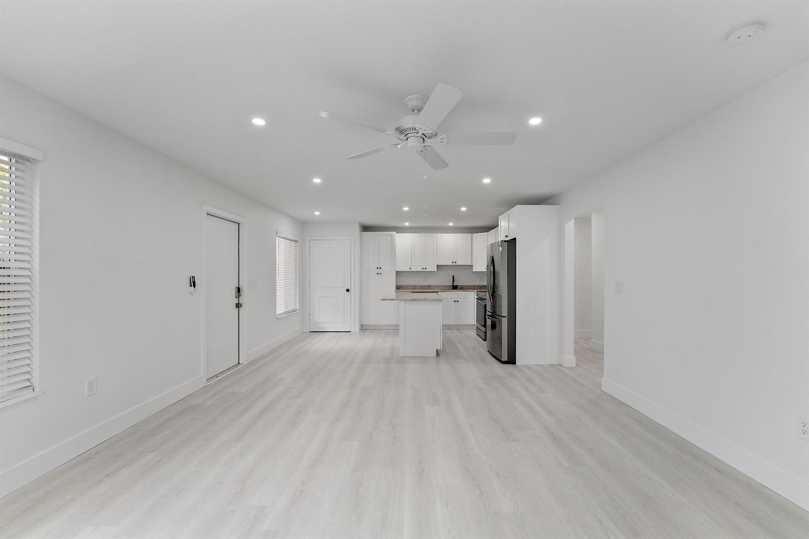 An open-concept kitchen and living area features white cabinetry, light wood-look flooring, and recessed lighting — 1279 Beach Road # 3, West Palm Beach FL 33404, WEST PALM BEACH, FL