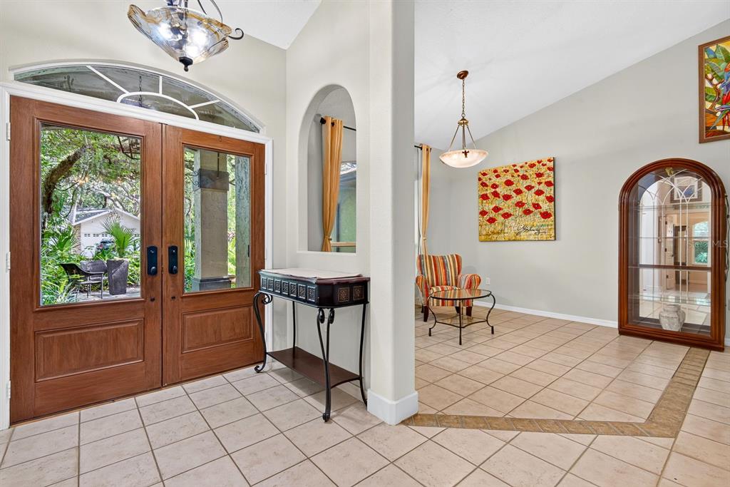 An entryway features double wood doors, tile flooring, an arched display niche, and a seating area — 2073 MISTY SUNRISE TRAIL, SARASOTA, FL