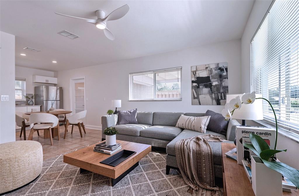 A living room features a gray sectional sofa, a wooden coffee table, and a dining area — 190 73RD AVENUE UNIT C, ST PETE BEACH, FL