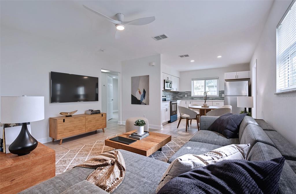 An open-concept living room and kitchen featuring a grey sectional sofa and light wood furniture — 190 73RD AVENUE UNIT C, ST PETE BEACH, FL