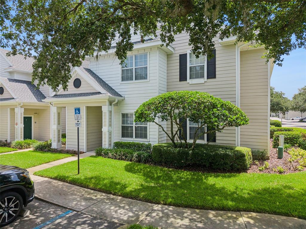 A two-story townhouse exterior with light siding, dark shutters, and a small front lawn — 200 SOUTHERN PECAN CIRCLE UNIT 104, WINTER GARDEN, FL
