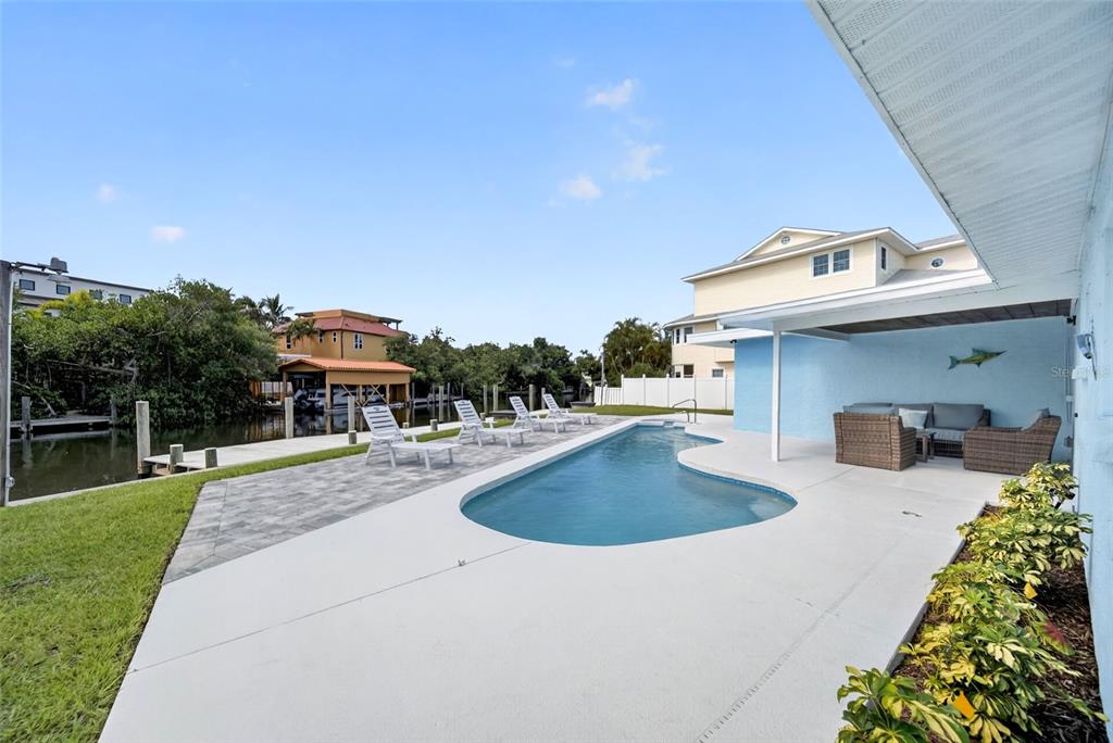 A swimming pool sits on a patio next to a canal with a boat dock — 507 59TH STREET, BRADENTON BEACH, FL