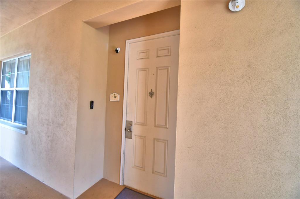 A white front door with a security camera and unit number 102 is shown — 7480 EXCITEMENT DRIVE UNIT 102, REUNION, FL