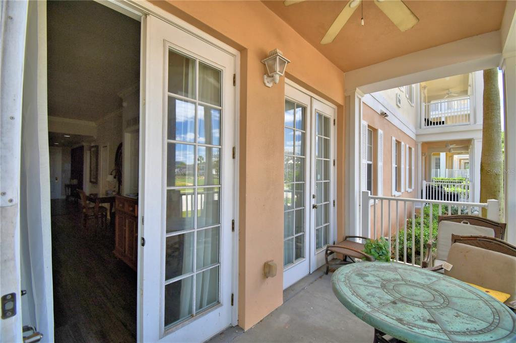 A covered patio features a round table, chairs, and glass doors leading into an interior room — 7480 EXCITEMENT DRIVE UNIT 102, REUNION, FL