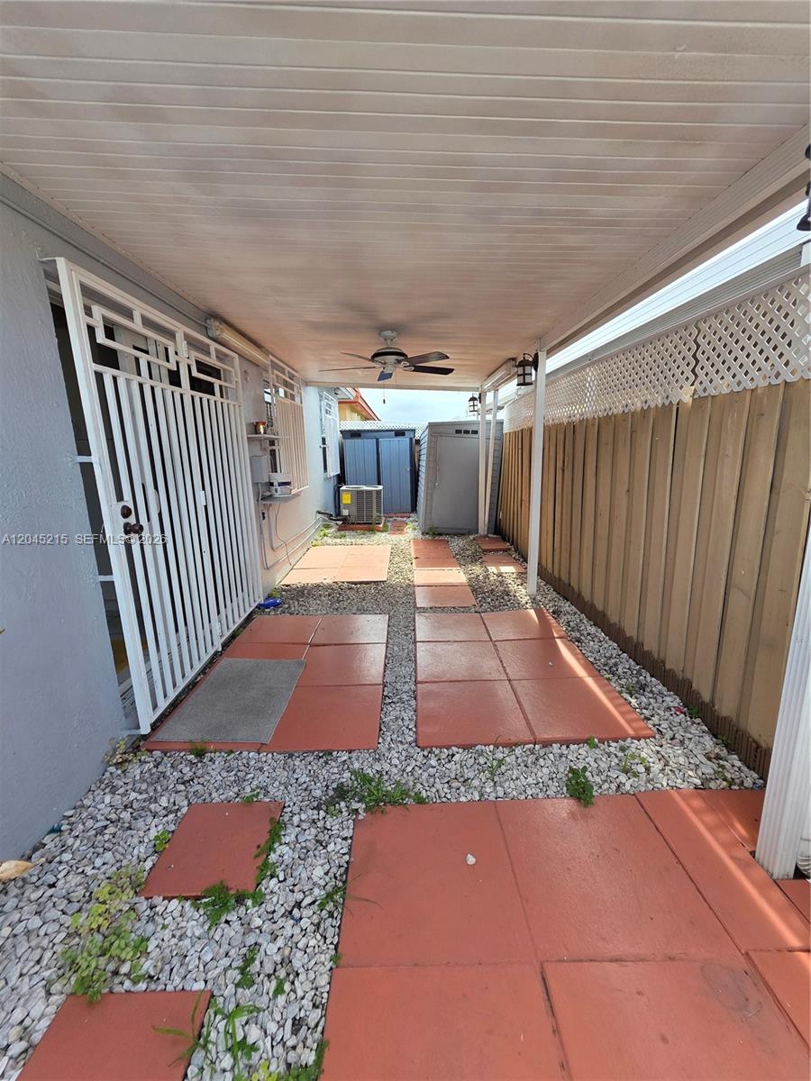 A covered outdoor patio features red pavers, gravel, a ceiling fan, and a metal gate — 8905 NW 121 ST # 0, Hialeah FL 33018, HIALEAH, FL