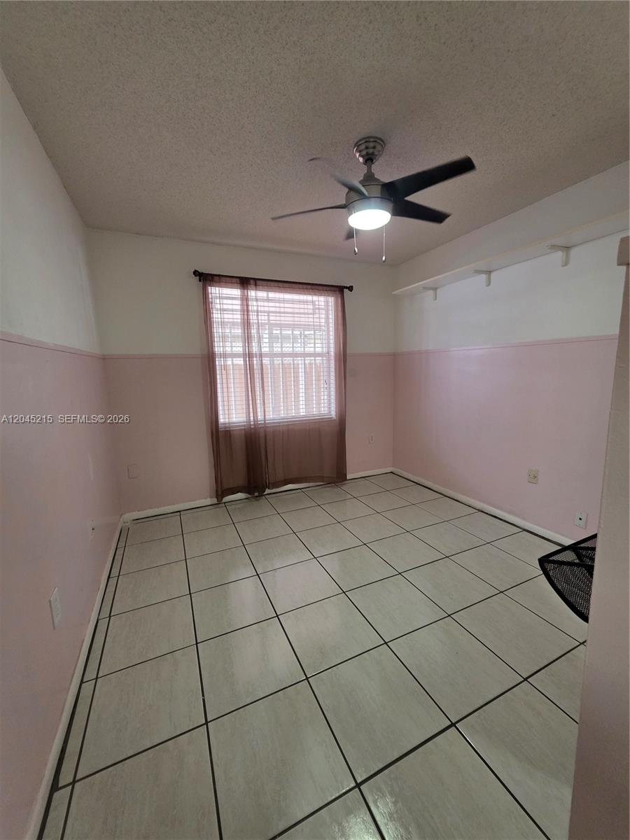 A bedroom features pink wainscoting, white walls, a ceiling fan, and light-colored tile flooring — 8905 NW 121 ST # 0, Hialeah FL 33018, HIALEAH, FL