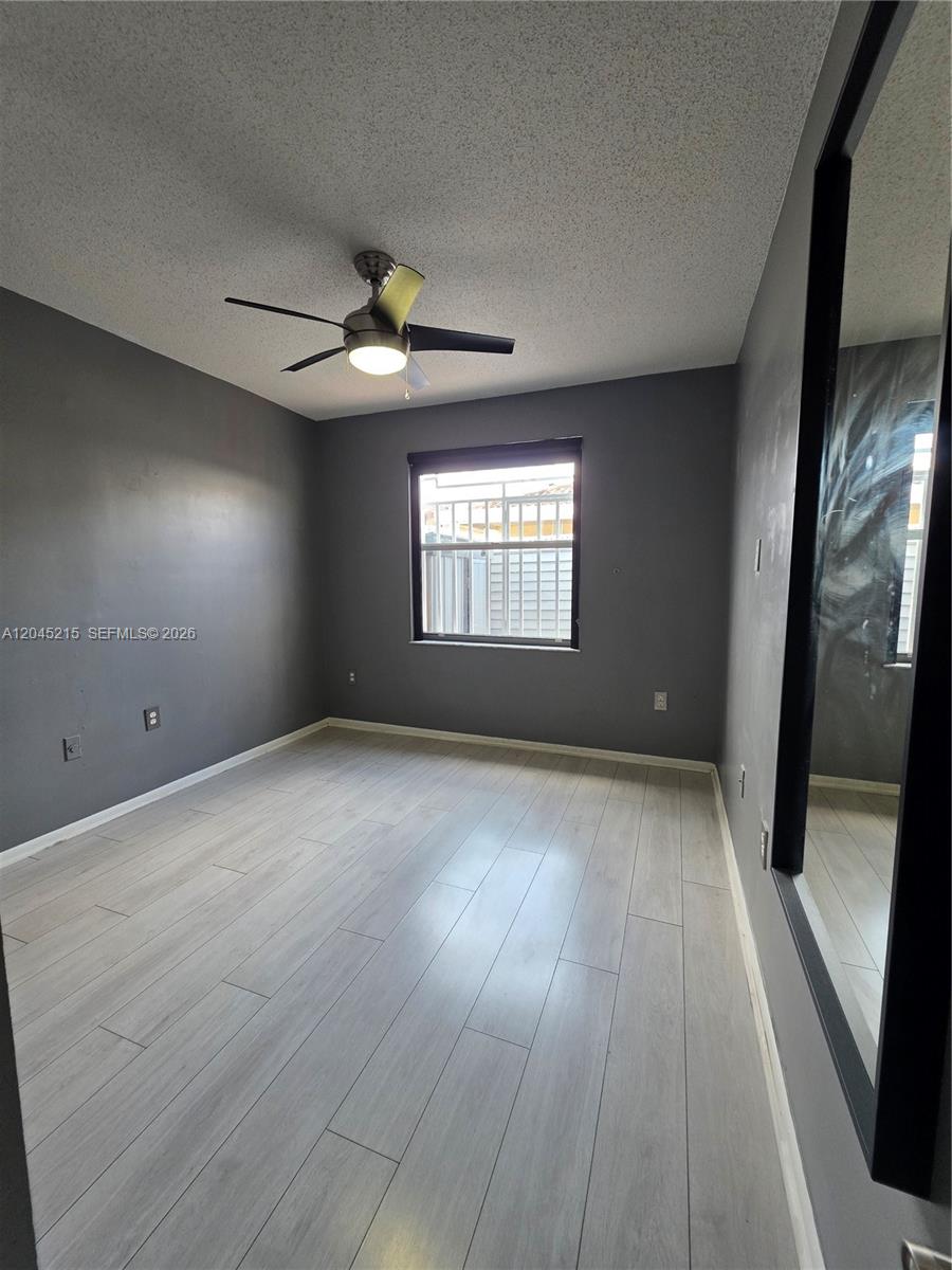 A bedroom features gray walls, light wood-look flooring, a ceiling fan, and a window — 8905 NW 121 ST # 0, Hialeah FL 33018, HIALEAH, FL