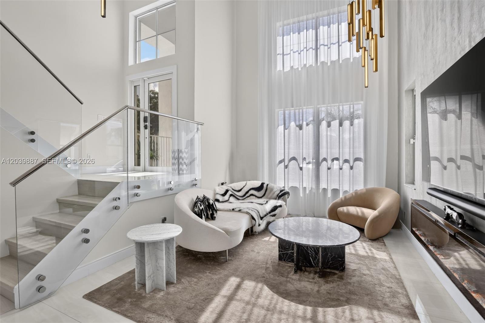 A modern living room features a glass-railed staircase, high ceilings, and a marble coffee table — 16233 Opal Creek Dr, Weston FL 33331, WESTON, FL