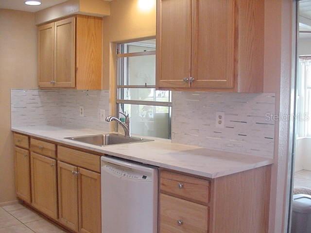 A kitchen features light wood cabinets, a white countertop, a stainless steel sink, and tiled backsplash — 533 CIRCLEWOOD DRIVE, VENICE, FL