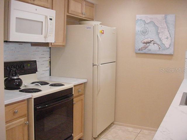 A kitchen features light wood cabinets, a white microwave, a white refrigerator, and a black stove — 533 CIRCLEWOOD DRIVE, VENICE, FL