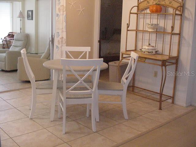A dining area features a round white table with four chairs and a metal baker's rack — 533 CIRCLEWOOD DRIVE, VENICE, FL