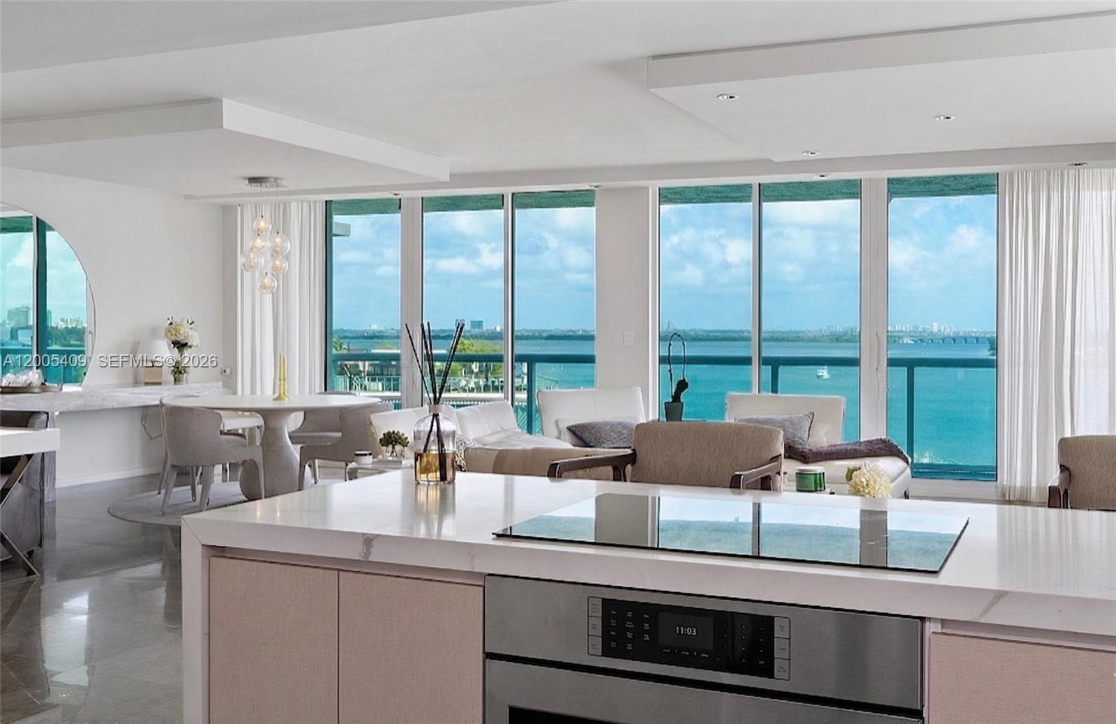 A modern kitchen island overlooks a living area with floor-to-ceiling windows and ocean views — 10 Venetian Way # 804, Miami Beach FL 33139, MIAMI BEACH, FL