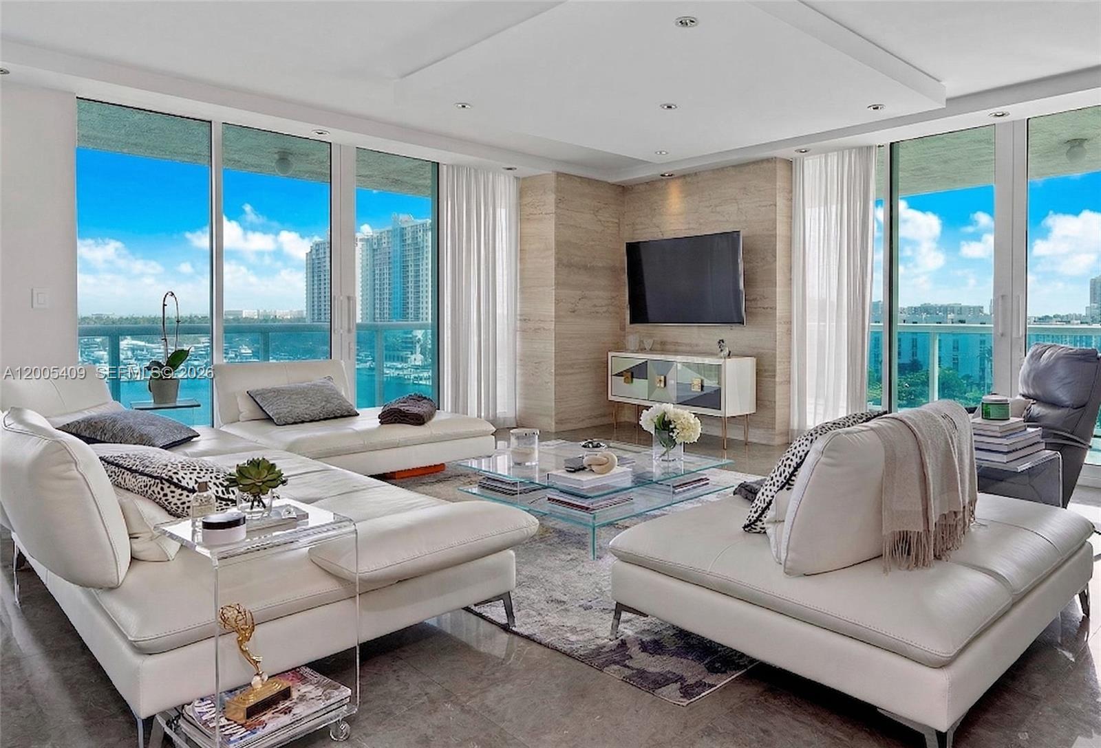 A modern living room features white leather sofas, a glass coffee table, and floor-to-ceiling windows — 10 Venetian Way # 804, Miami Beach FL 33139, MIAMI BEACH, FL