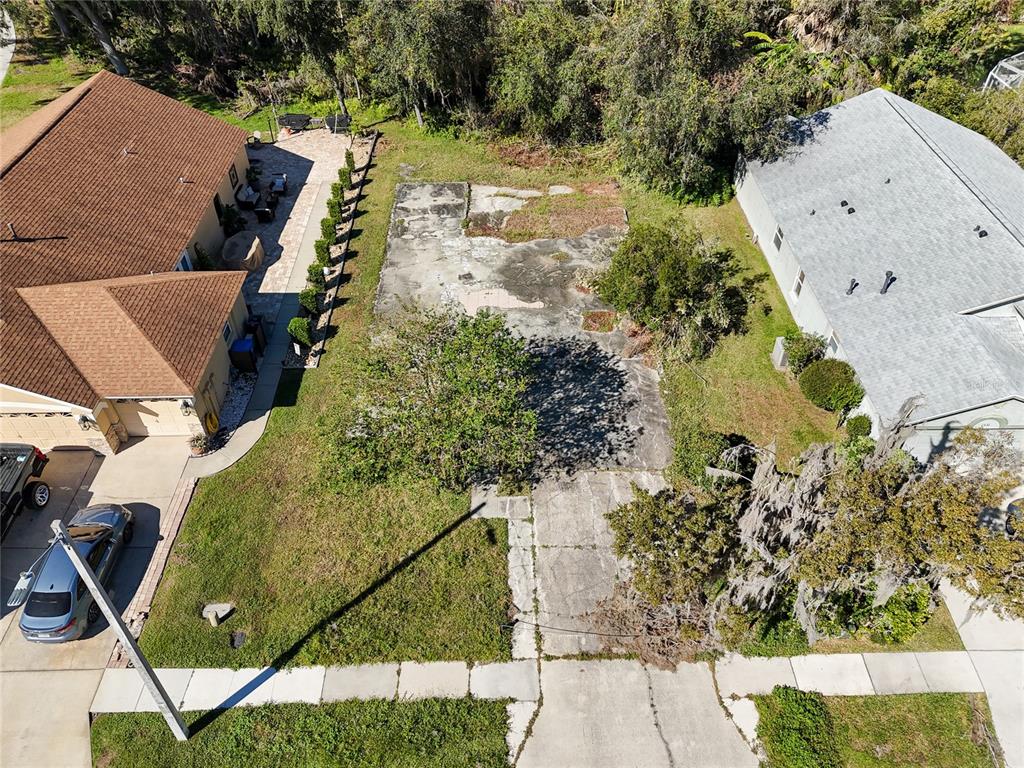 An aerial view shows a vacant concrete lot situated between two residential houses — 1323 BAYTHORN DRIVE, WESLEY CHAPEL, FL