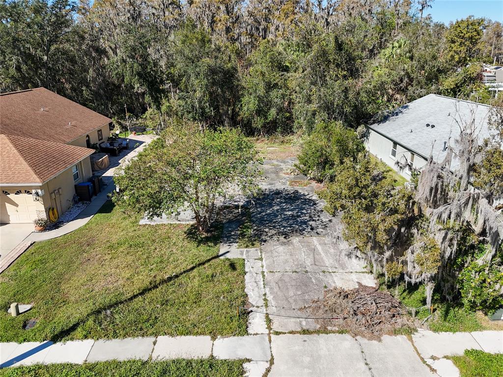 An aerial view shows a vacant residential lot situated between two houses with mature trees — 1323 BAYTHORN DRIVE, WESLEY CHAPEL, FL