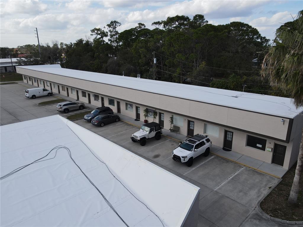 An aerial view shows a long, single-story commercial building with a white roof and parking — 2111 S RIDGEWOOD AVENUE, EDGEWATER, FL