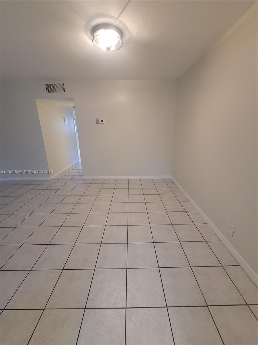 A room with light-colored tile flooring, beige walls, and a central ceiling light fixture — 1340 NE 28th Ave # 129, Pompano Beach FL 33062, POMPANO BEACH, FL