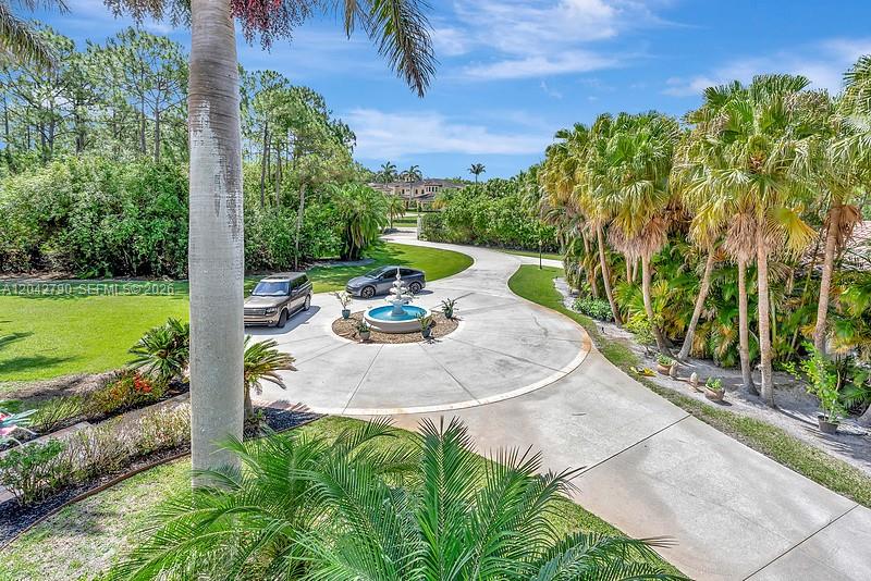 A circular driveway with a central fountain leads to a house surrounded by palm trees — 2584 SE Ranch Acres Cir, Jupiter FL 33478, JUPITER, FL