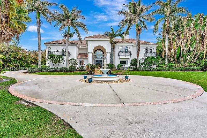 A large two-story white house features a circular driveway and a central water fountain — 2584 SE Ranch Acres Cir, Jupiter FL 33478, JUPITER, FL