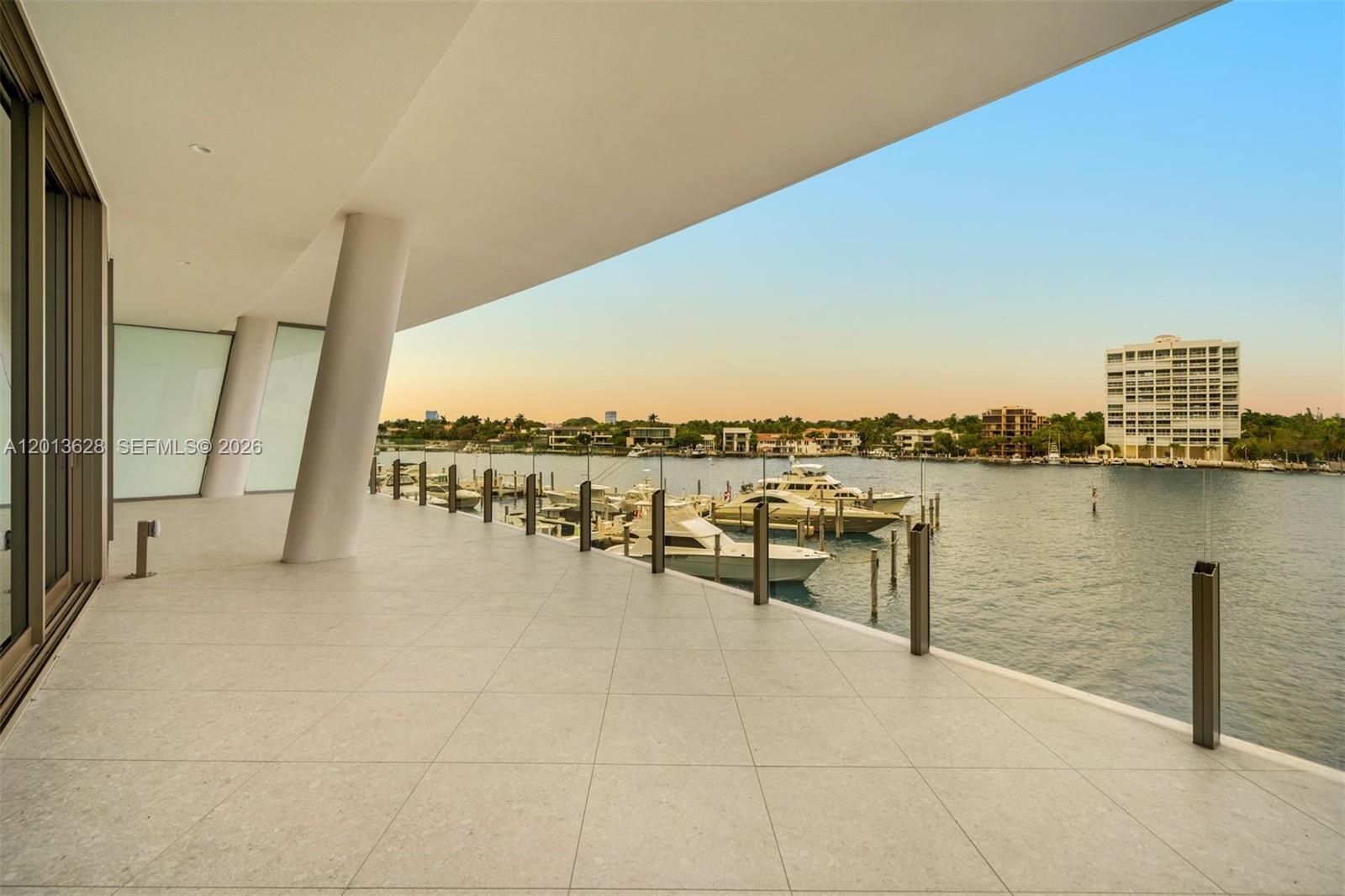 A spacious balcony with tile flooring overlooks a waterway filled with docked yachts — 5 Grove Isle Dr # S302, Coconut Grove FL 33133, COCONUT GROVE, FL