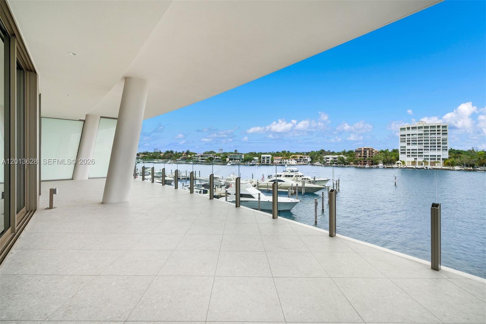 A spacious, tiled balcony overlooks a waterway filled with docked yachts and distant buildings — 5 Grove Isle Dr # S302, Coconut Grove FL 33133, COCONUT GROVE, FL