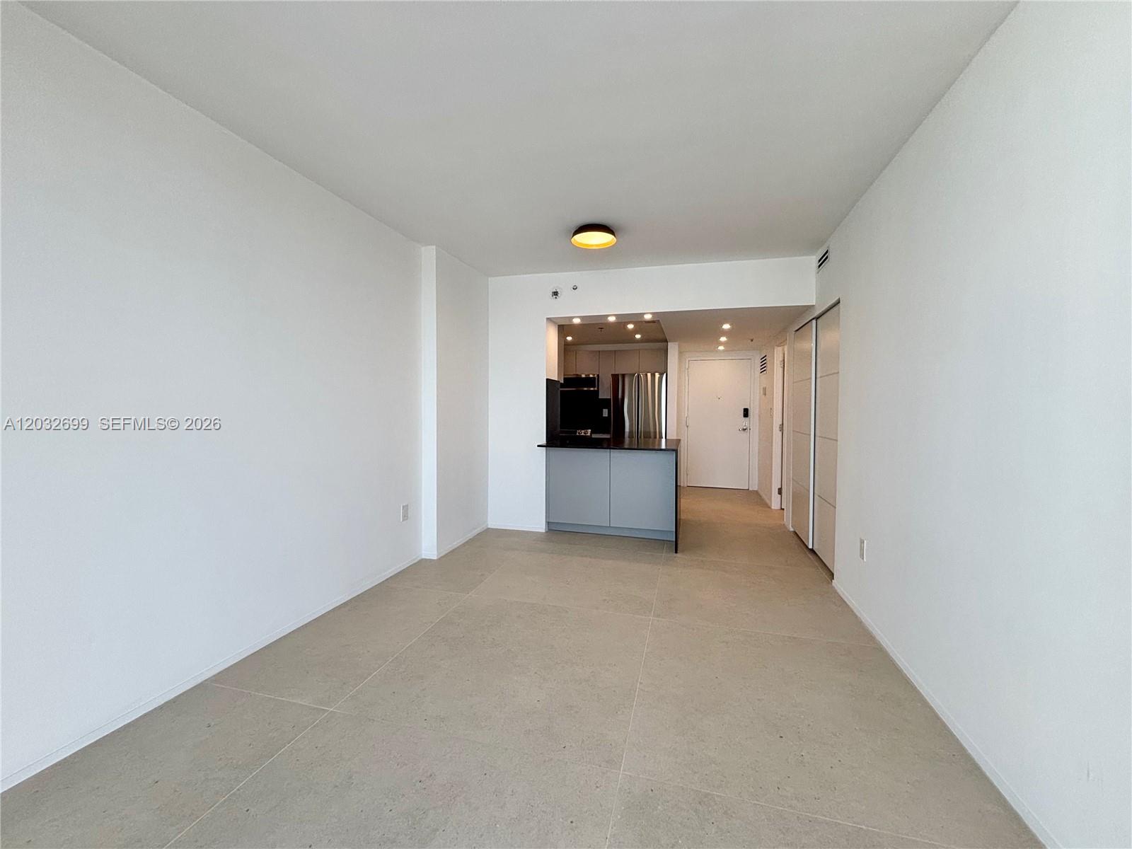 This room features light-colored tile flooring, white walls, and an open kitchen area — 2829 Indian Creek Dr # 604, Miami Beach FL 33140, MIAMI BEACH, FL