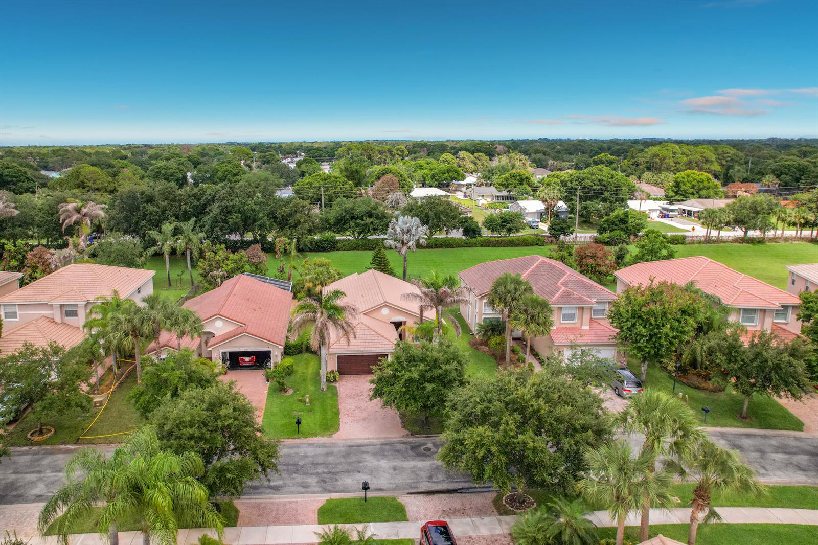 An aerial view shows a row of suburban houses with tiled roofs and landscaped yards — 2045 Grey Falcon Circle SW, Vero Beach FL 32962, VERO BEACH, FL