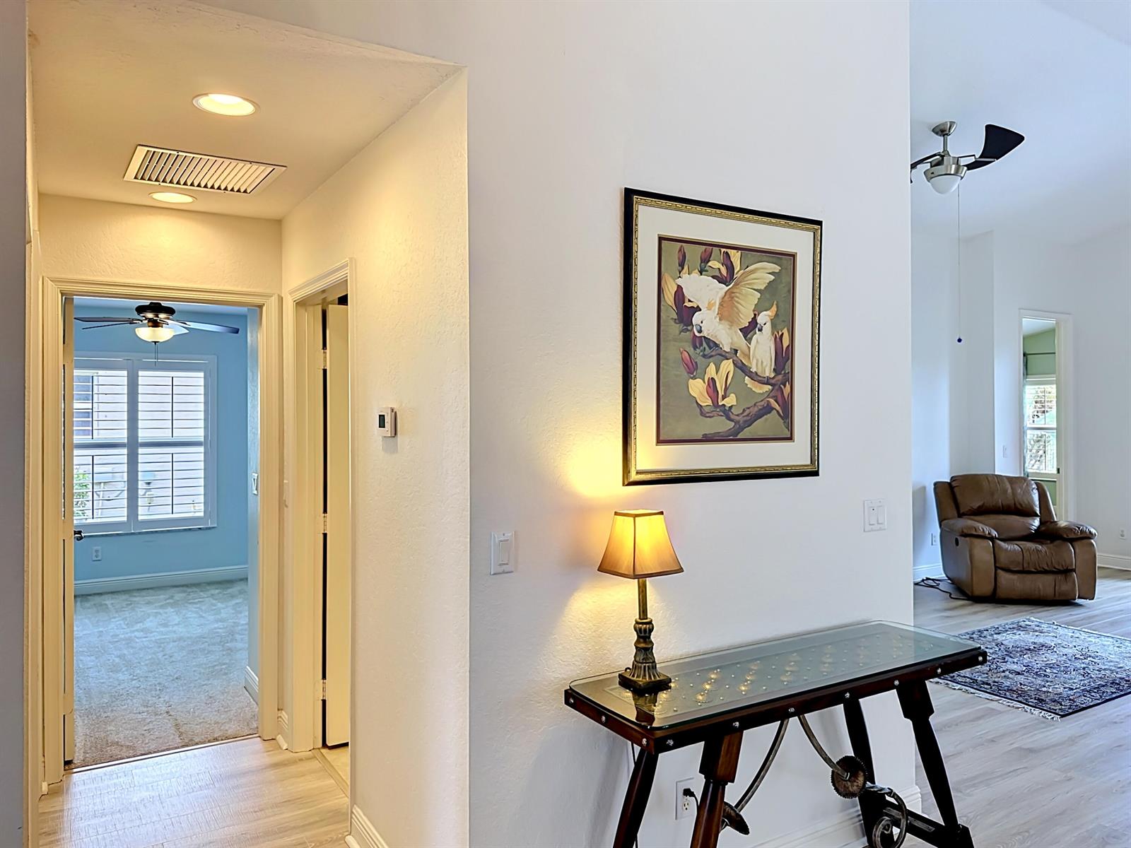 A hallway with a console table and lamp leads to a bedroom and living area — 2045 Grey Falcon Circle SW, Vero Beach FL 32962, VERO BEACH, FL