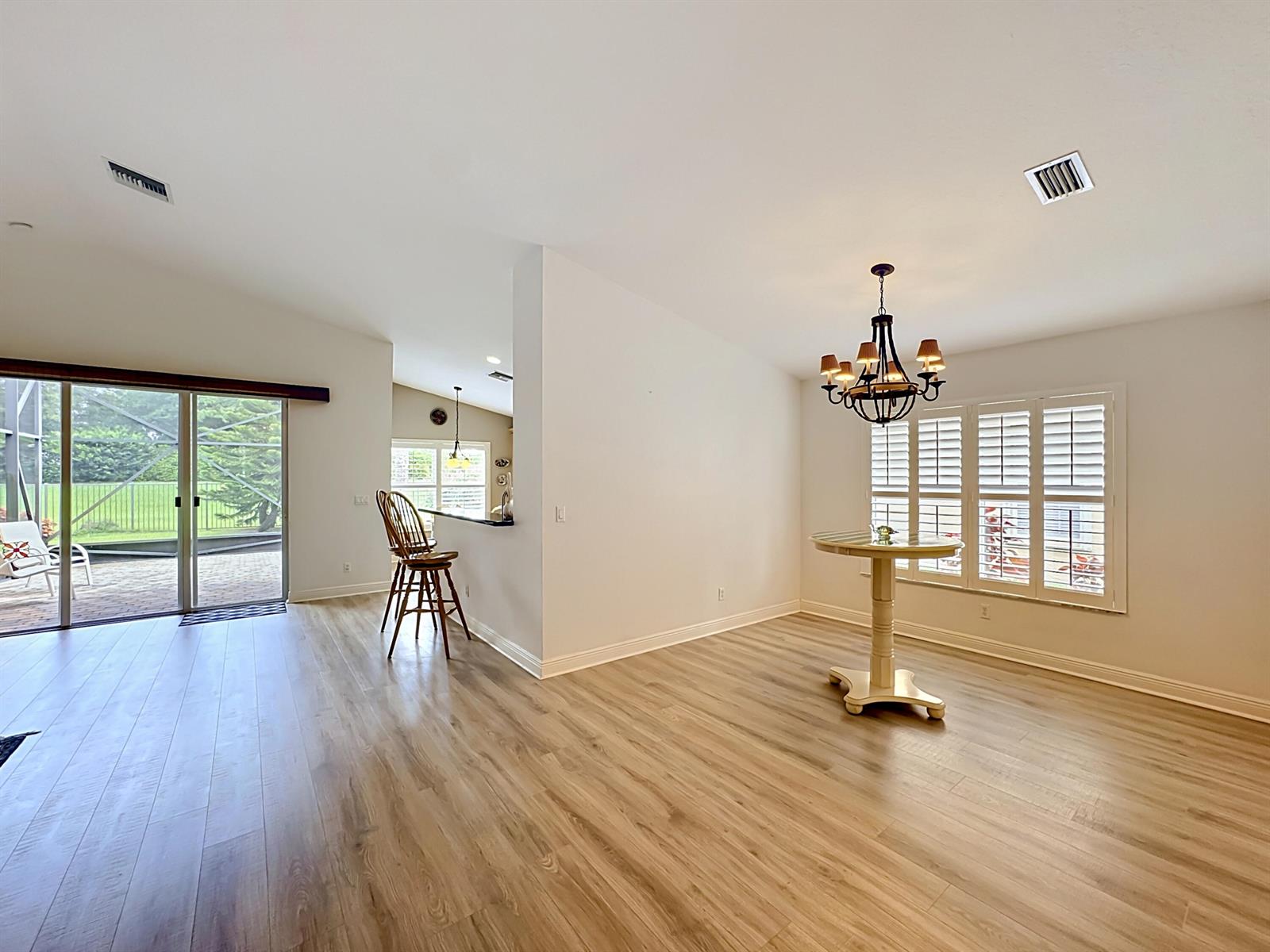 A dining area with a chandelier and a breakfast bar overlooking a patio — 2045 Grey Falcon Circle SW, Vero Beach FL 32962, VERO BEACH, FL