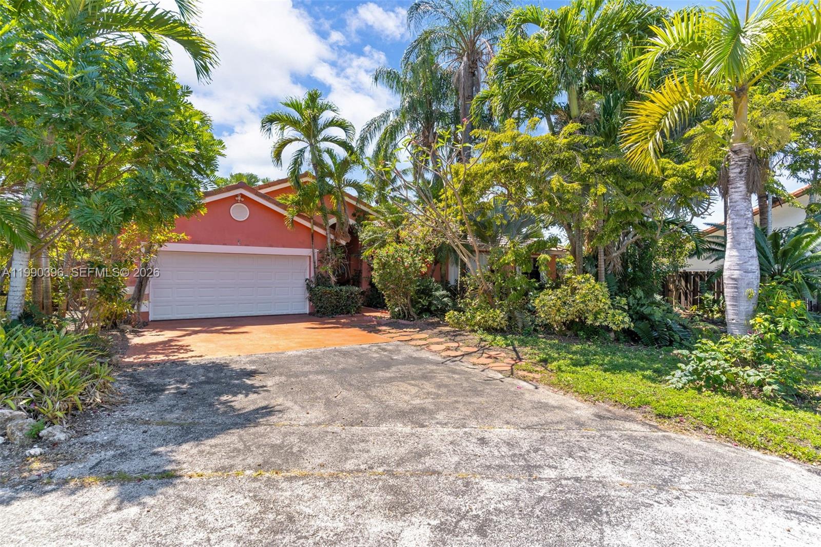 A single-story house with a terracotta exterior, a white garage door, and lush tropical landscaping — 15012 SW 45th Ln, Miami FL 33185, MIAMI, FL
