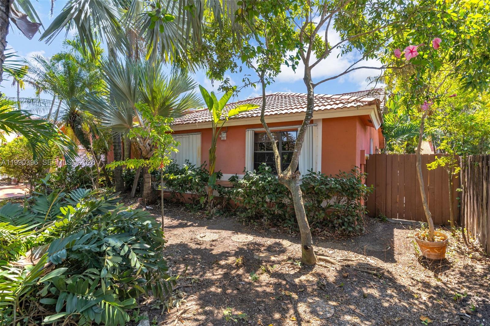 A peach-colored house with a tiled roof is surrounded by lush tropical landscaping — 15012 SW 45th Ln, Miami FL 33185, MIAMI, FL