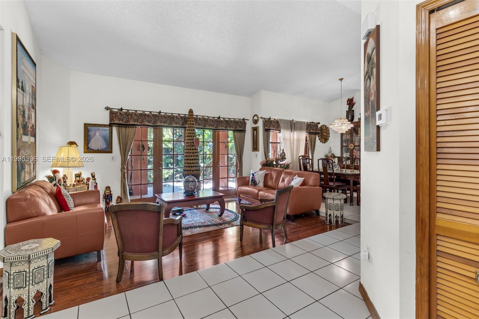 A living room with leather sofas, wood flooring, and glass doors leading to a patio — 15012 SW 45th Ln, Miami FL 33185, MIAMI, FL