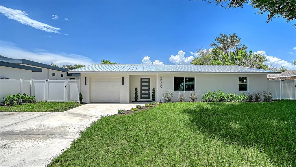 A single-story house with a white exterior, metal roof, and a concrete driveway — 2329 ROSE STREET, SARASOTA, FL