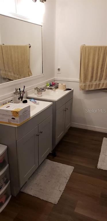 A bathroom features a double vanity with gray cabinets, white countertops, and a large mirror — 1089 GREENSKEEP DRIVE, KISSIMMEE, FL