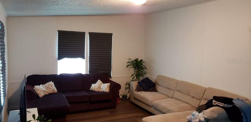 A living room features a dark purple sectional sofa, a beige sofa, and window blinds — 1089 GREENSKEEP DRIVE, KISSIMMEE, FL