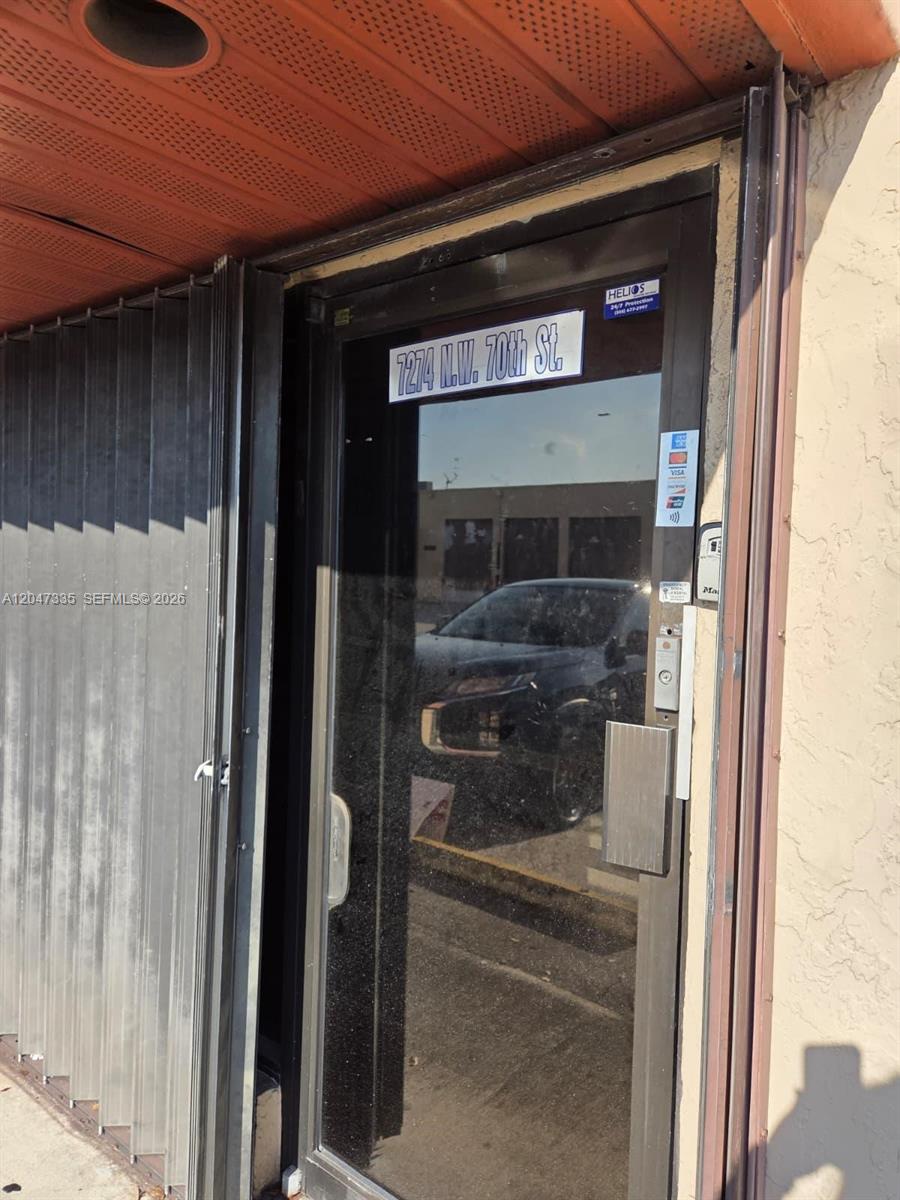 A glass entry door with a metal security gate stands at the building entrance — 7274 NW 70th St, Miami FL 33166, MIAMI, FL