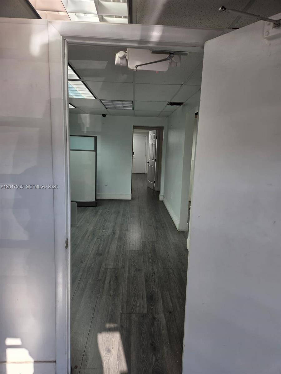 A view through a doorway shows an office hallway with gray wood-look flooring — 7274 NW 70th St, Miami FL 33166, MIAMI, FL