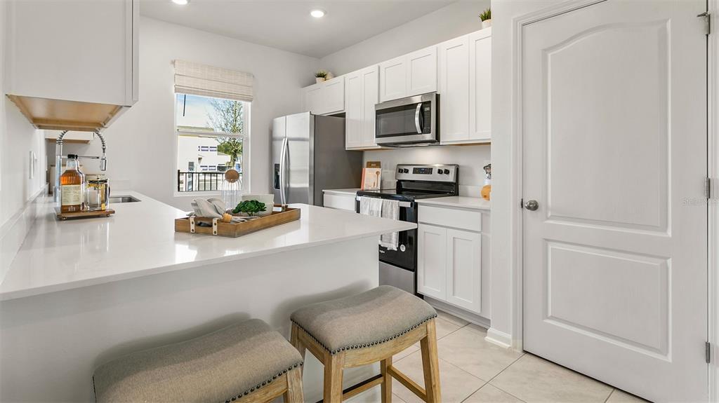 A modern kitchen features white cabinets, stainless steel appliances, and a breakfast bar with stools — 257 PALMETTO RIDGE ROAD, ST AUGUSTINE, FL