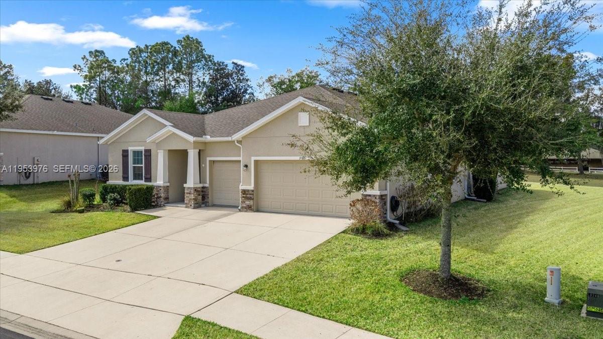 A tan single-story house features a two-car garage, a concrete driveway, and a front lawn — 5608 SW 50th Ct, Ocala FL 34474, OCALA, FL