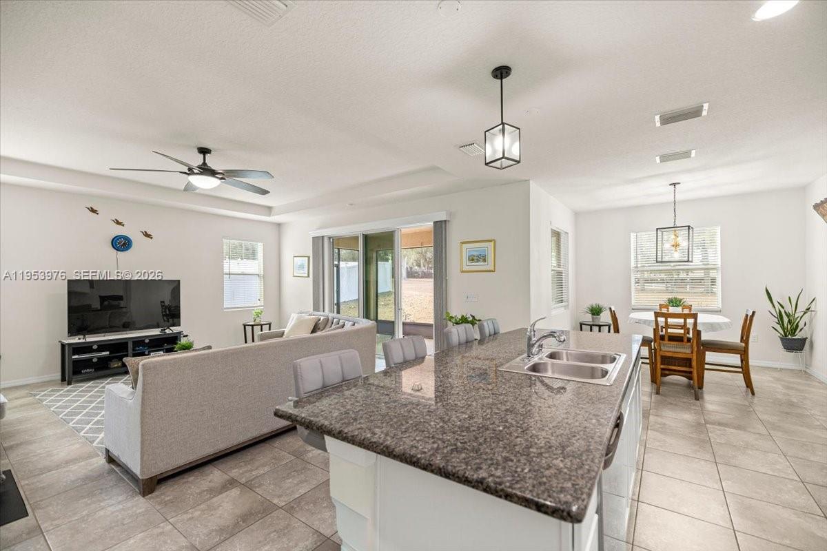 An open-concept kitchen with granite countertops overlooks a living room and dining area — 5608 SW 50th Ct, Ocala FL 34474, OCALA, FL