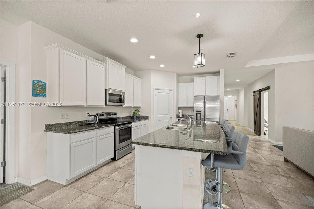 A modern kitchen features white cabinets, granite countertops, stainless steel appliances, and a central island — 5608 SW 50th Ct, Ocala FL 34474, OCALA, FL