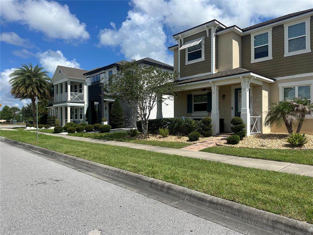 A street-level view of three suburban houses with front porches and manicured landscaping — 2791 RAPOLLO DRIVE, KISSIMMEE, FL