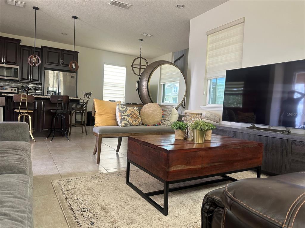 A living room features a wooden coffee table, a gray bench, and an open kitchen — 2791 RAPOLLO DRIVE, KISSIMMEE, FL
