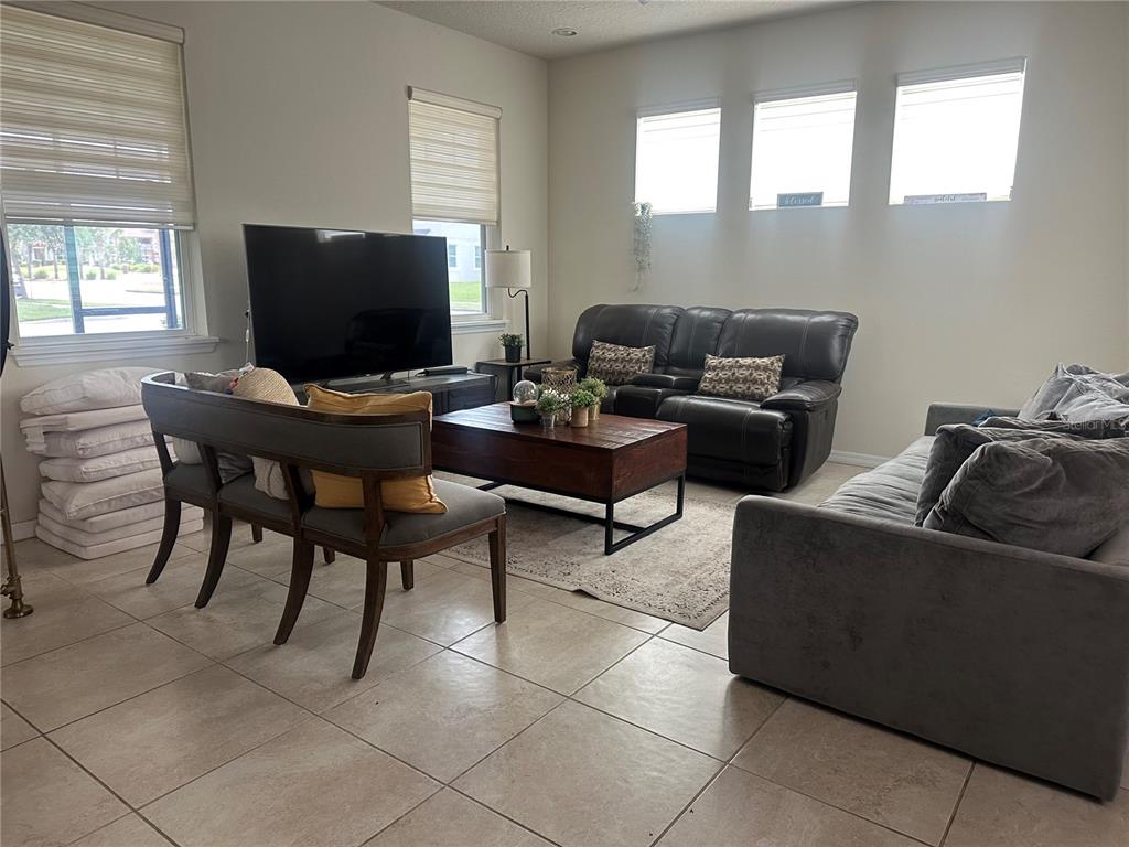 A living room features tile flooring, a television, a coffee table, and multiple seating areas — 2791 RAPOLLO DRIVE, KISSIMMEE, FL