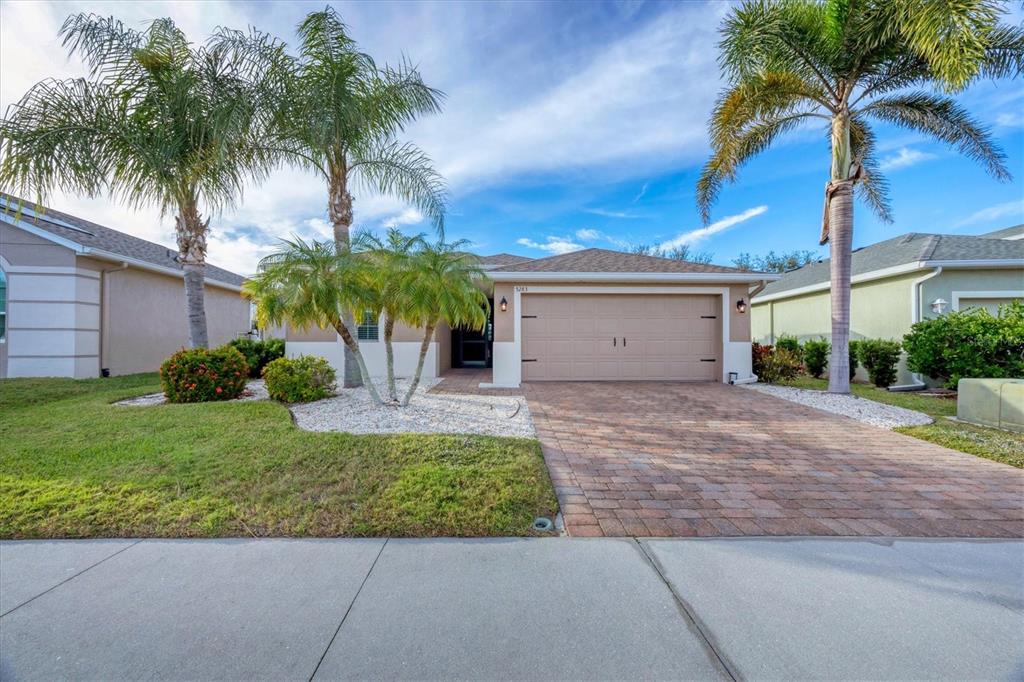 A single-story house with a paved driveway, a two-car garage, and several palm trees — 5283 CANYONLAND WAY, VENICE, FL